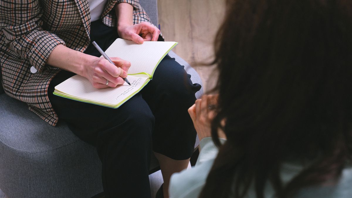 A counselor writing notes during a one-to-one counseling session
